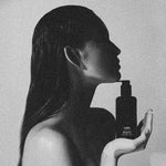 Model holding LBH Skincare AHA Cleanser black glass bottle