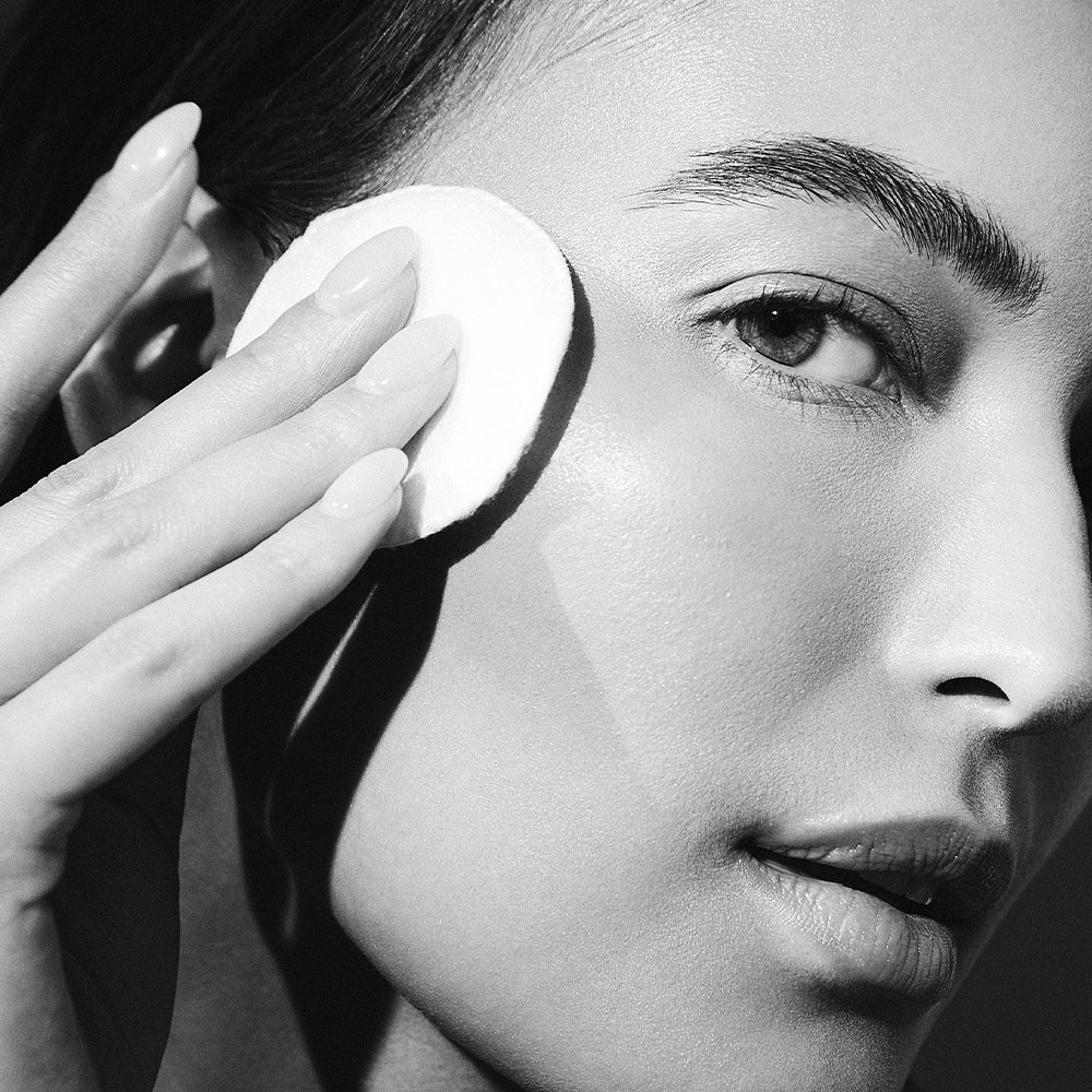 Model applying LBH Skincare Exfoliating Toner to the face with cotton